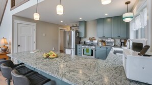 A kitchen with granite countertops, stainless steel appliances, and teal cabinetry. - Lakefront Bucksport Home w/ Fire Pit + Gas Grill! (Bucksport)