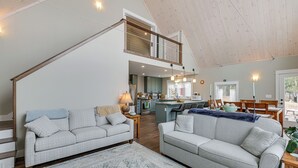 A spacious living area with a high ceiling, a staircase, a kitchen, and a dining area. - Lakefront Bucksport Home w/ Fire Pit + Gas Grill! (Bucksport)