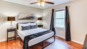 A bedroom with a bed, two bedside tables, a ceiling fan, a window with curtains, and a wall-mounted artwork. - Mebane Home w/ Private Yard: Steps to Downtown! (Mebane)