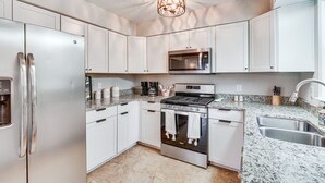 A modern kitchen with white cabinets, stainless steel appliances, a granite countertop, and a skylight. - Mebane Home w/ Private Yard: Steps to Downtown! (Mebane)