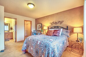 A bedroom with a large bed, bedside lamps, a small table with a lamp, and a wall-mounted decoration.