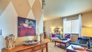 Een woonkamer met een houten salontafel, een bank, een lamp en een schilderij aan de muur.