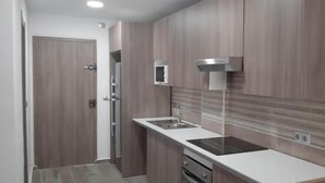 A modern kitchen with wooden cabinets, a stainless steel sink, and a microwave. - Studio PREMIUM Vera Playa Naturist  (Vera)