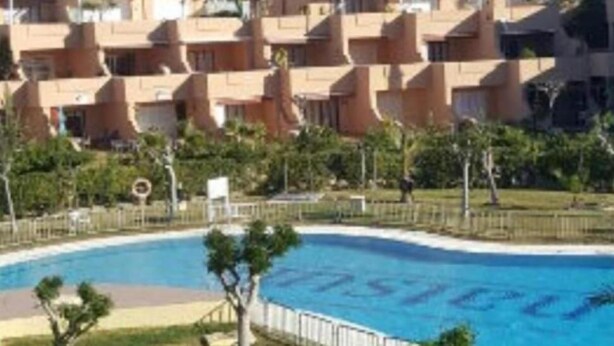 A swimming pool surrounded by a fence, with a view of apartment buildings in the background. - Studio PREMIUM Vera Playa Naturist  (Vera)