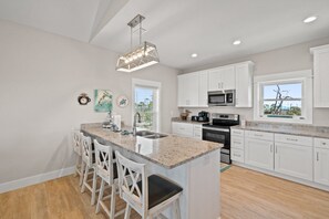 A modern kitchen with white cabinets, a granite countertop, and a central island with bar stools.