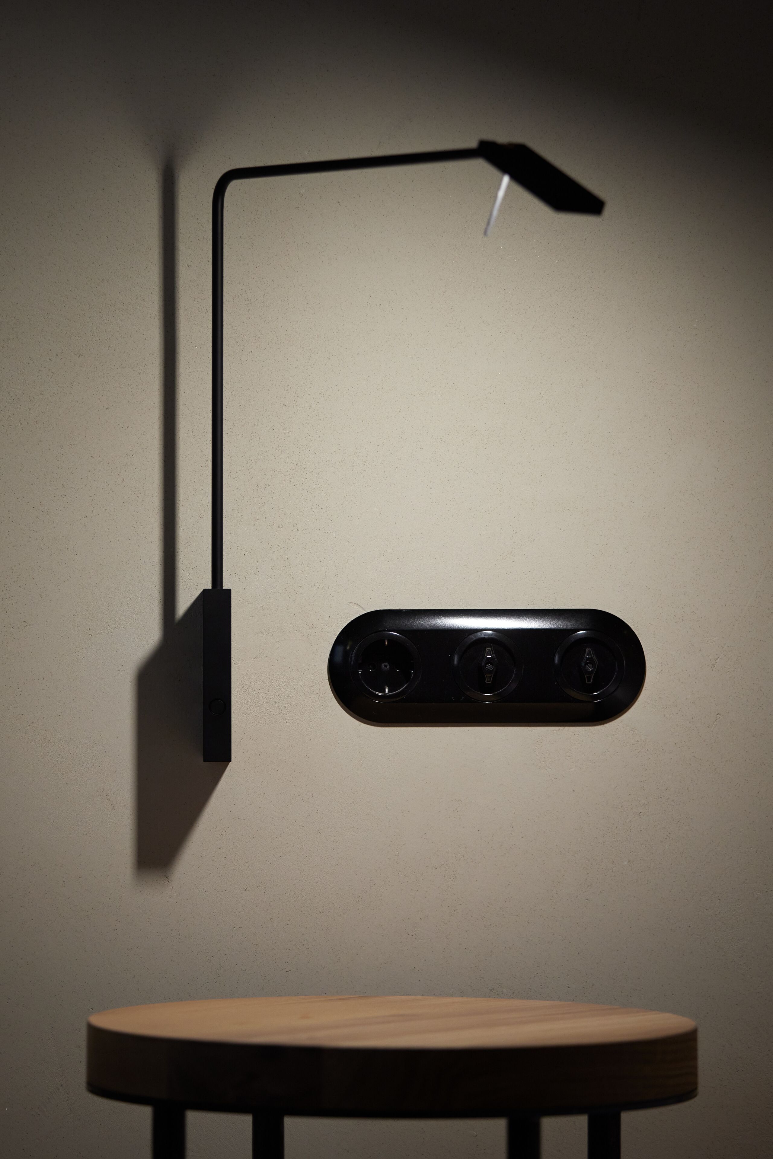 A wall-mounted light fixture with a rectangular base and a long arm extending to the left.