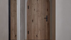 Un pasillo con una puerta de madera y un espejo en la pared izquierda.