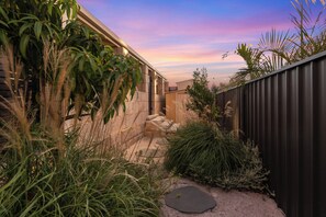 A garden with a stone pathway, a wooden fence, and various plants. - 5BR and pool luxury home (Kinross)