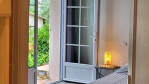 A bedroom with a bed, a window, and a sliding glass door leading to a balcony.
