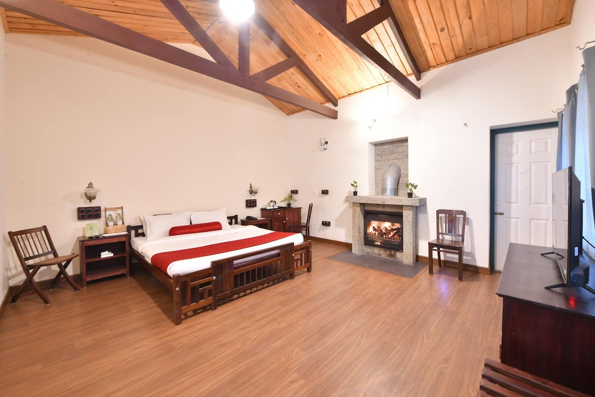 Un dormitorio con una cama de madera, chimenea, televisor y escritorio.