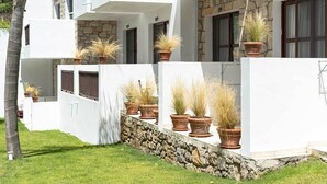 Een modern gebouw met witte muren en stenen accenten, met diverse potplanten aan de buitenkant.