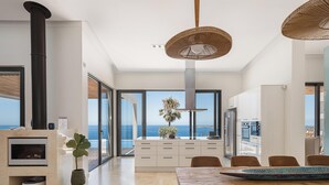 Een moderne keuken met uitzicht op zee, een eethoek met een houten tafel, en een groot raam.
