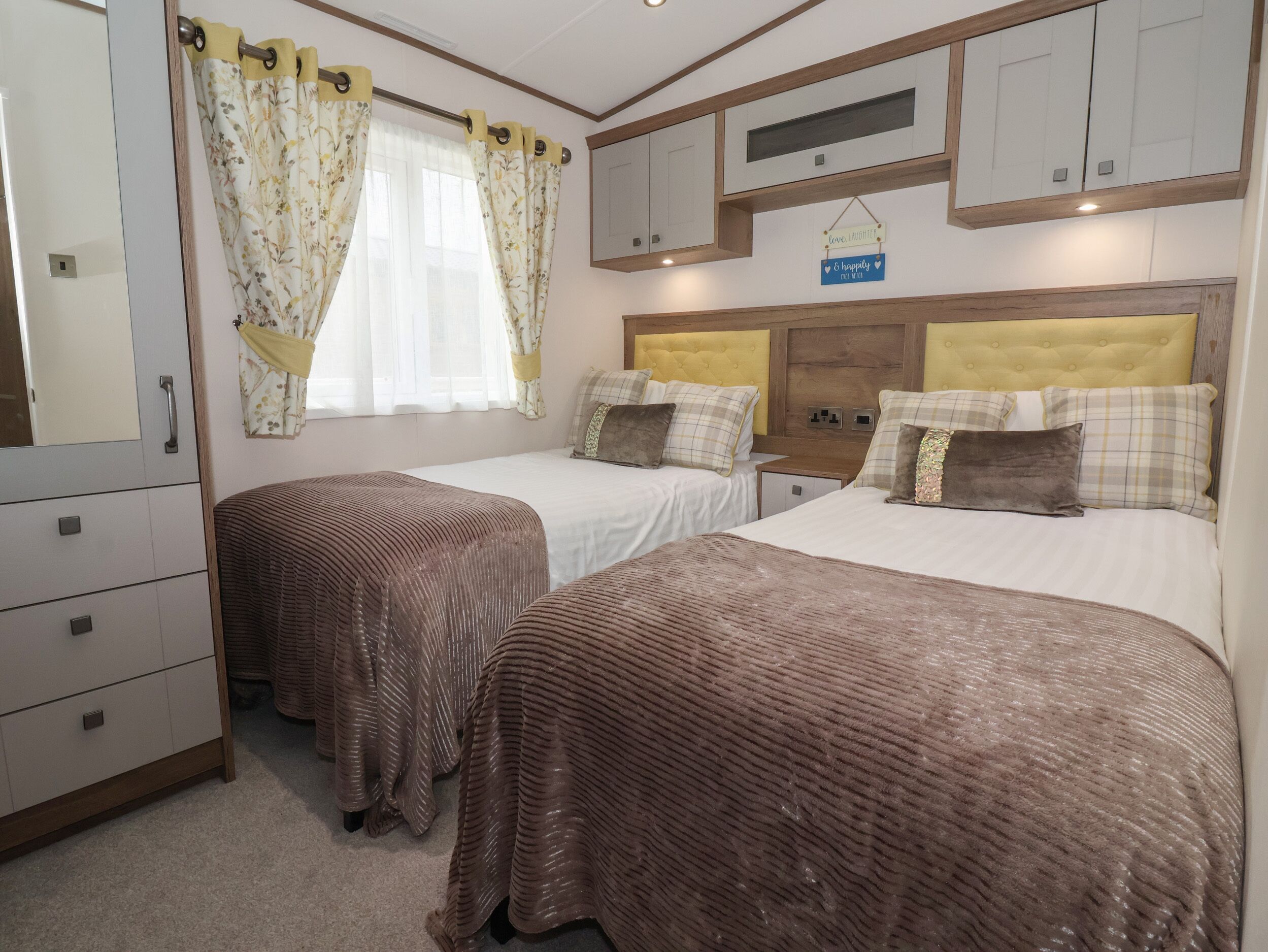 A bedroom with two beds, a wardrobe, a mirror, and a sign above the beds.