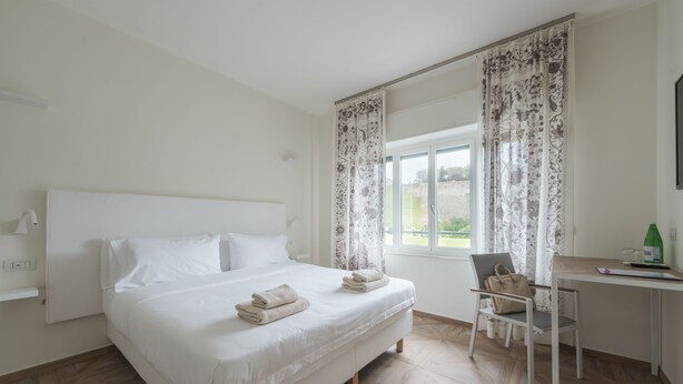 Un dormitorio con cama, escritorio, silla y ventana con cortinas.