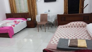 A hotel room with two beds, a desk, a chair, and a TV on the wall. - Kishoreganj Resort (Kishoreganj Sadar)