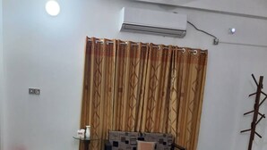A living room with a sofa, a coffee table, a patterned rug, a coat rack, and a ceiling fan. - Kishoreganj Resort (Kishoreganj Sadar)