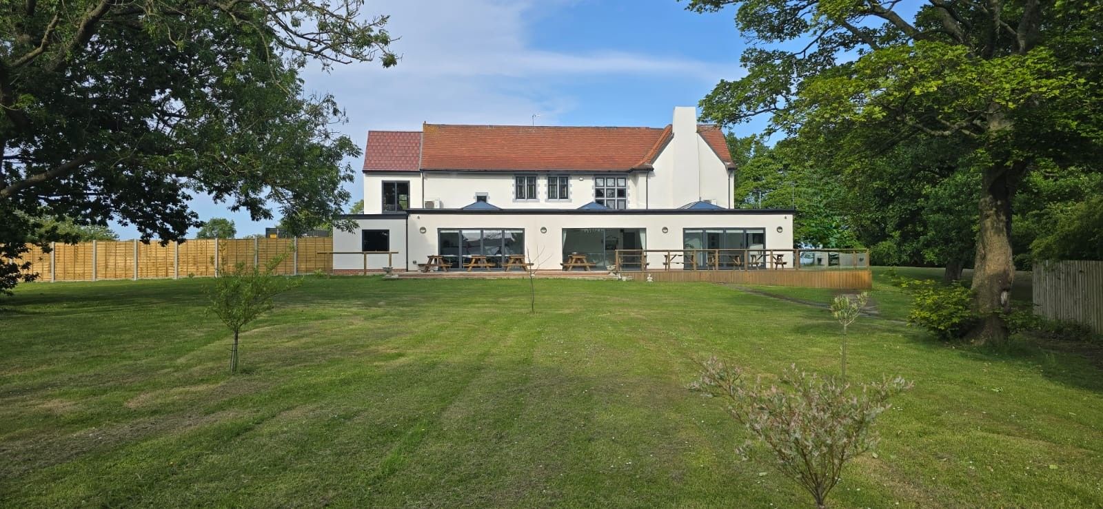 A modern two-story house with a large lawn and a wooden fence.