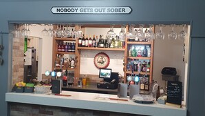 Zona de bar con un letrero que dice 'NADIE SALE SÓBRIO'.