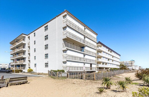 Ett hotell med flera våningar och balkonger, beläget nära en sandstrand.