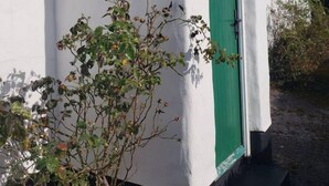 A white building with a green door and a small garden area in front. - Traditional Holiday Cottage Louisburgh. (Louisburgh)