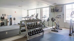 Une salle de sport équipée de matériel d’exercice, d’un porte-haltères et d’un grand miroir.
