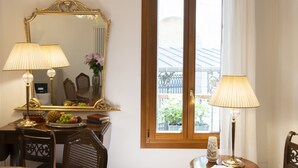 A room with a wooden ceiling, a large mirror, two lamps, a dining table with chairs, and a window with curtains. - Giò&Giò Apartments (Venice)
