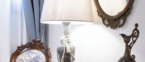 A wooden dresser with a lamp, a mirror, and a decorative vase.