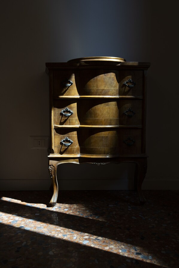 A wooden cabinet with multiple drawers and handles, positioned against a wall with a tiled floor.