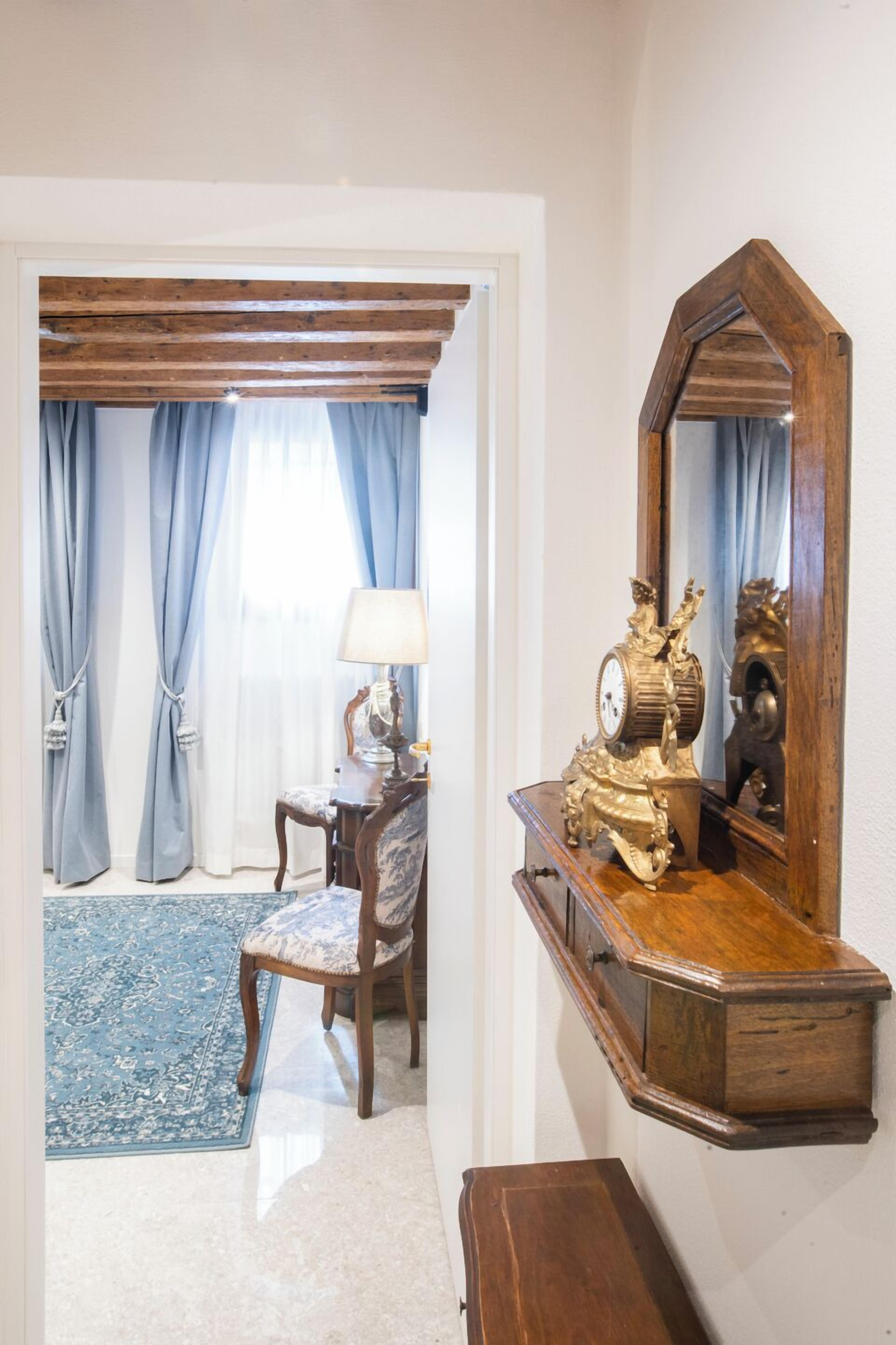 Une pièce avec un bureau en bois, une chaise, une lampe et un grand miroir.