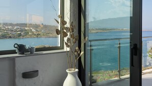 A modern room with a large window overlooking a body of water and a distant landscape. - Villa Anton by Cura Villas Collection (Chania)