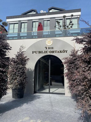 The entrance to The Public Ortaköy with a modern design, featuring a clear archway and potted plants. - The Public Ortakoy (Istanbul)