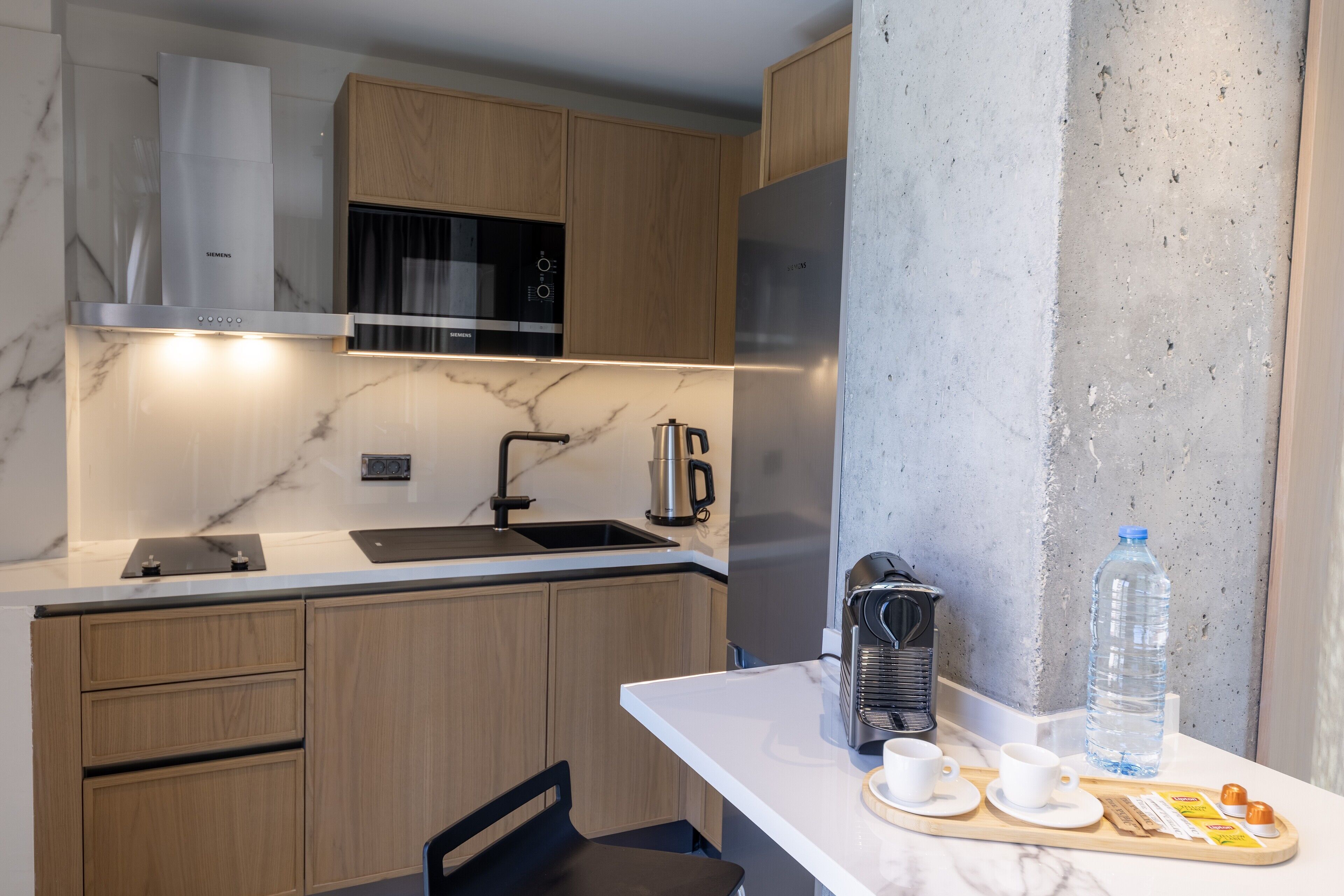 Una cocina moderna con armarios de madera, una campana extractora de acero inoxidable, un microondas y un refrigerador.