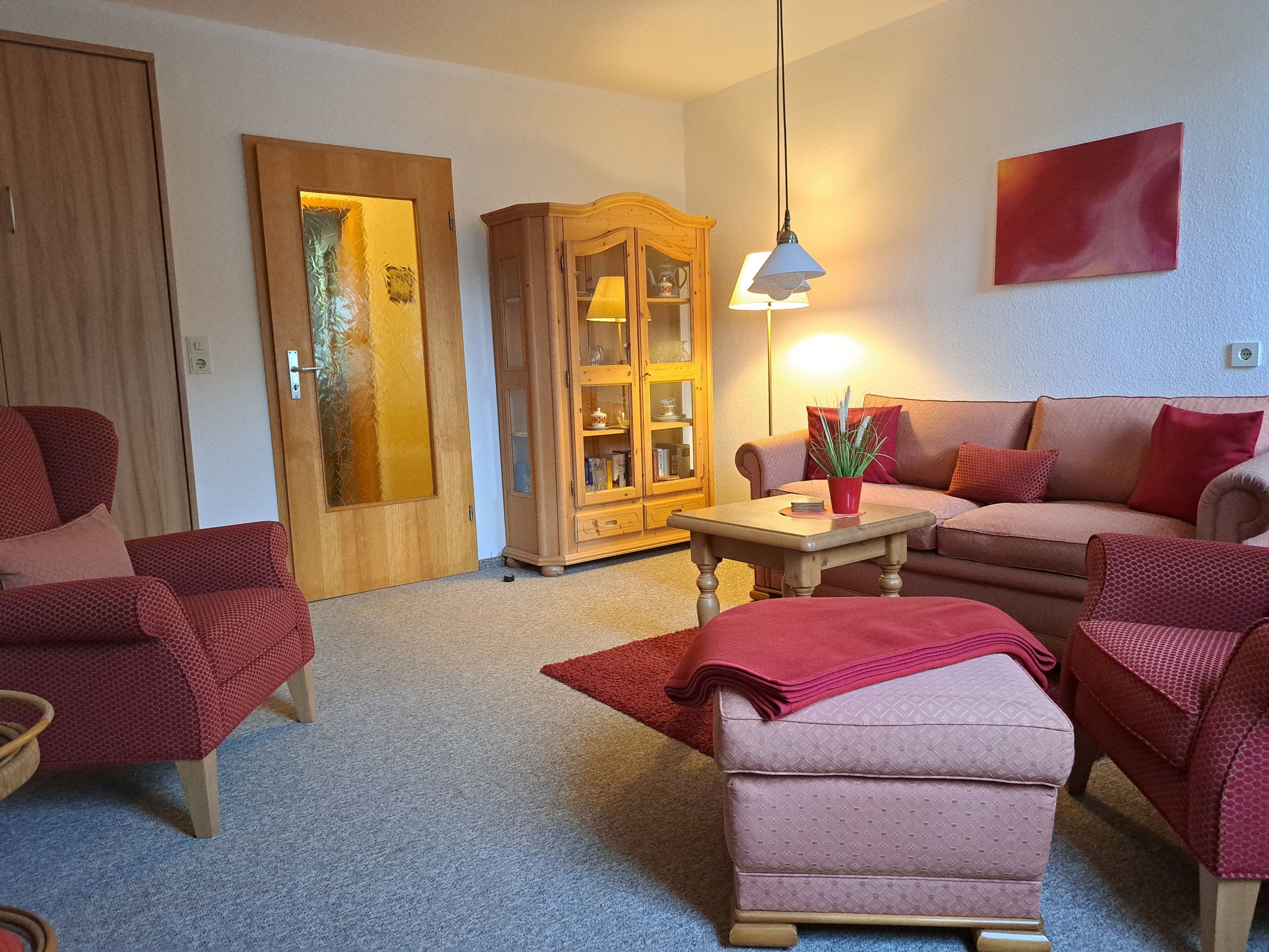 Ein Wohnzimmer mit Sofa, Sesseln, einem Schrank und einem Tisch.