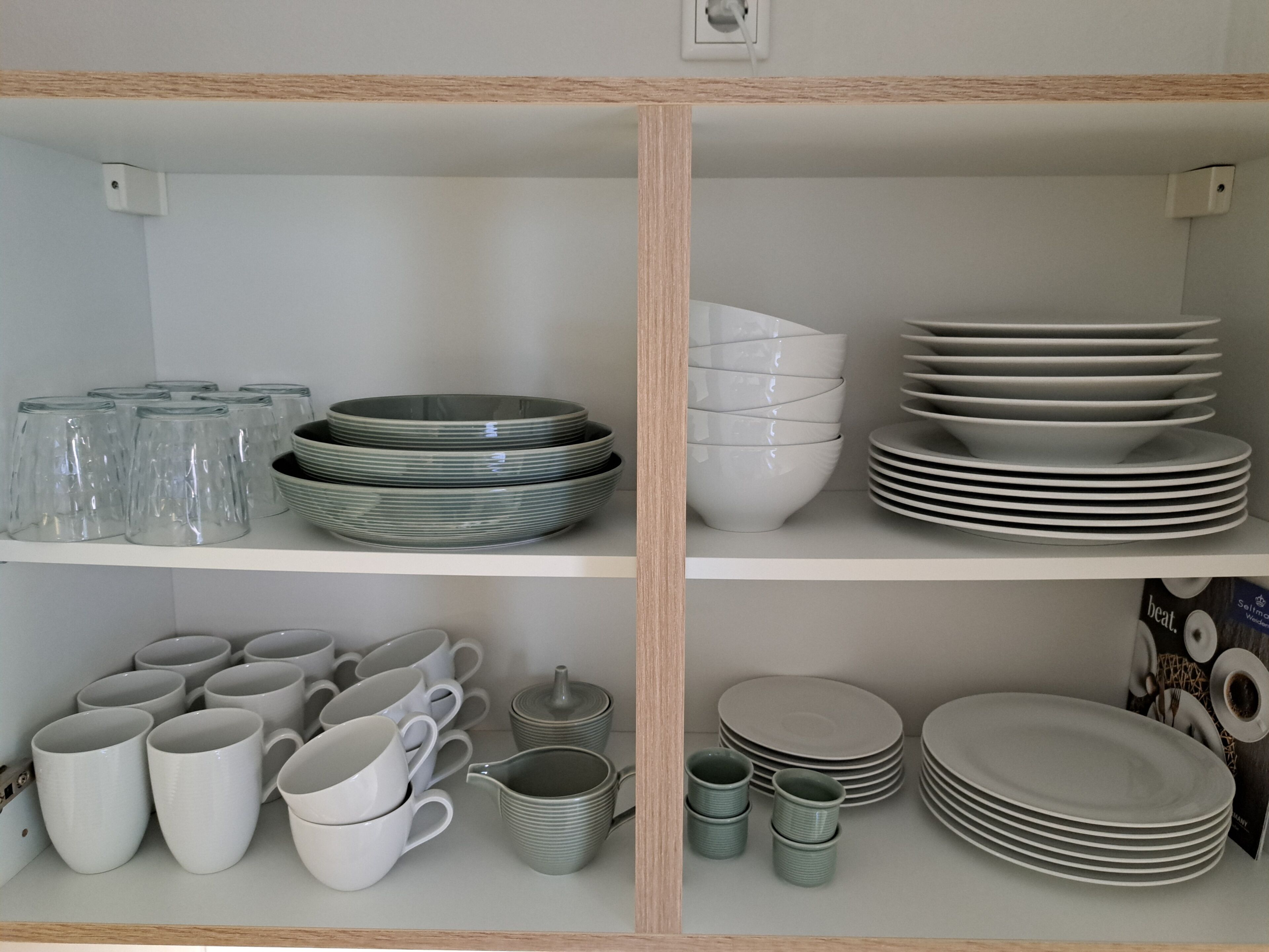 A neatly organized kitchen with shelves holding various dishes, cups, and bowls.