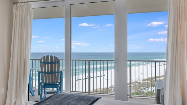 A bedroom with a large sliding glass door leading to a balcony with a beach view. - Book Now for Fall! Oceanfront! (Panama City Beach)