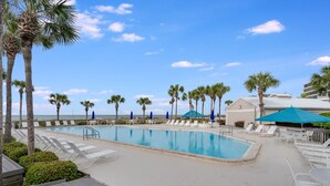 A pool area with lounge chairs and umbrellas, surrounded by palm trees and a clear sky. - Book Now for Fall! Oceanfront! (Panama City Beach)