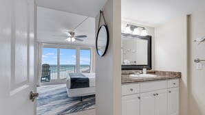 A hotel room with a balcony, a ceiling fan, a large mirror, and a bathroom with a sink and vanity. - Book Now for Fall! Oceanfront! (Panama City Beach)