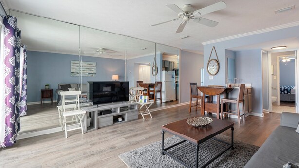 A modern living room with a flat-screen TV, a ceiling fan, and a dining area with a table and chairs. - Fall Dates Available! Quick Walk to Beach! Perfect for Families! (Panama City Beach)