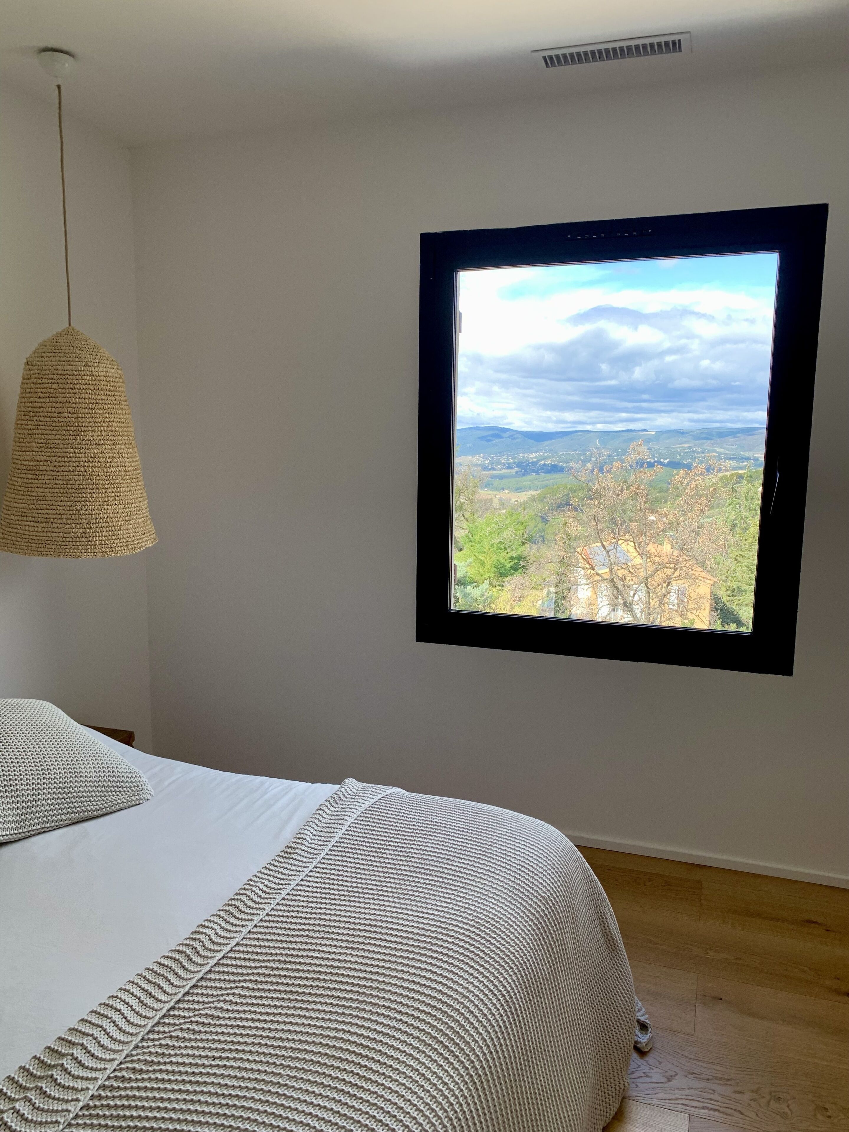 A bedroom with a large window offering a view of a mountainous landscape.