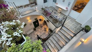 A multi-level interior with a staircase, a seating area with tables and chairs, and various potted plants. - Donna Grazia  (Gallipoli)
