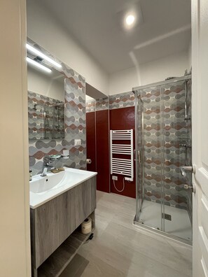 A modern bathroom with a large mirror, two sinks, a shower, and patterned walls. - Donna Grazia  (Gallipoli)
