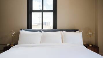 A neatly made bed with white linens, a dark headboard, and two bedside lamps with round bases.