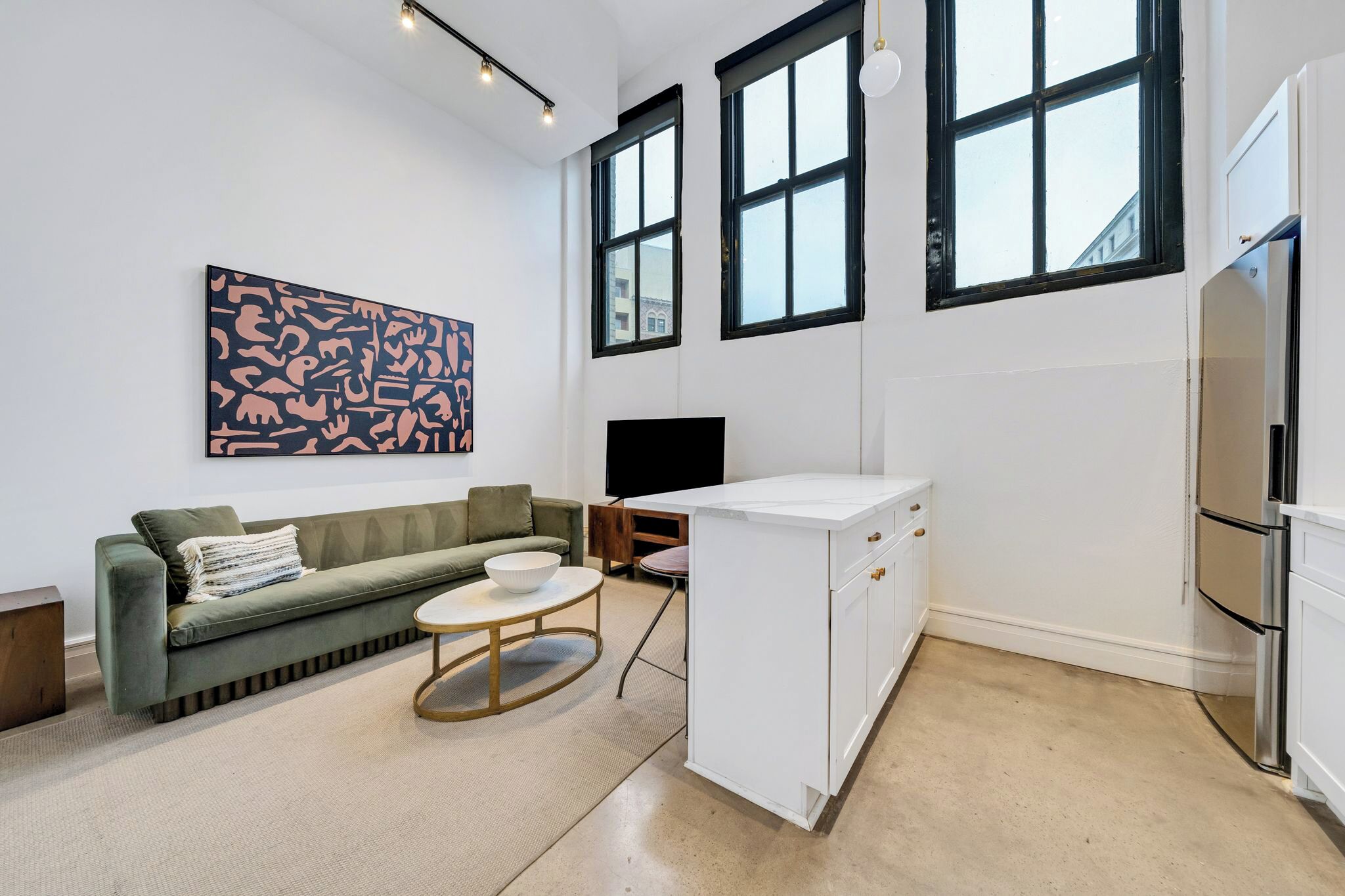 A modern living room with a green sofa, a coffee table, and a large abstract painting on the wall.