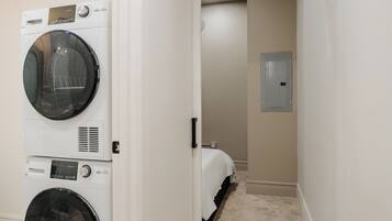 Een wasserette met gestapelde wasmachines en een bed in de aangrenzende kamer.