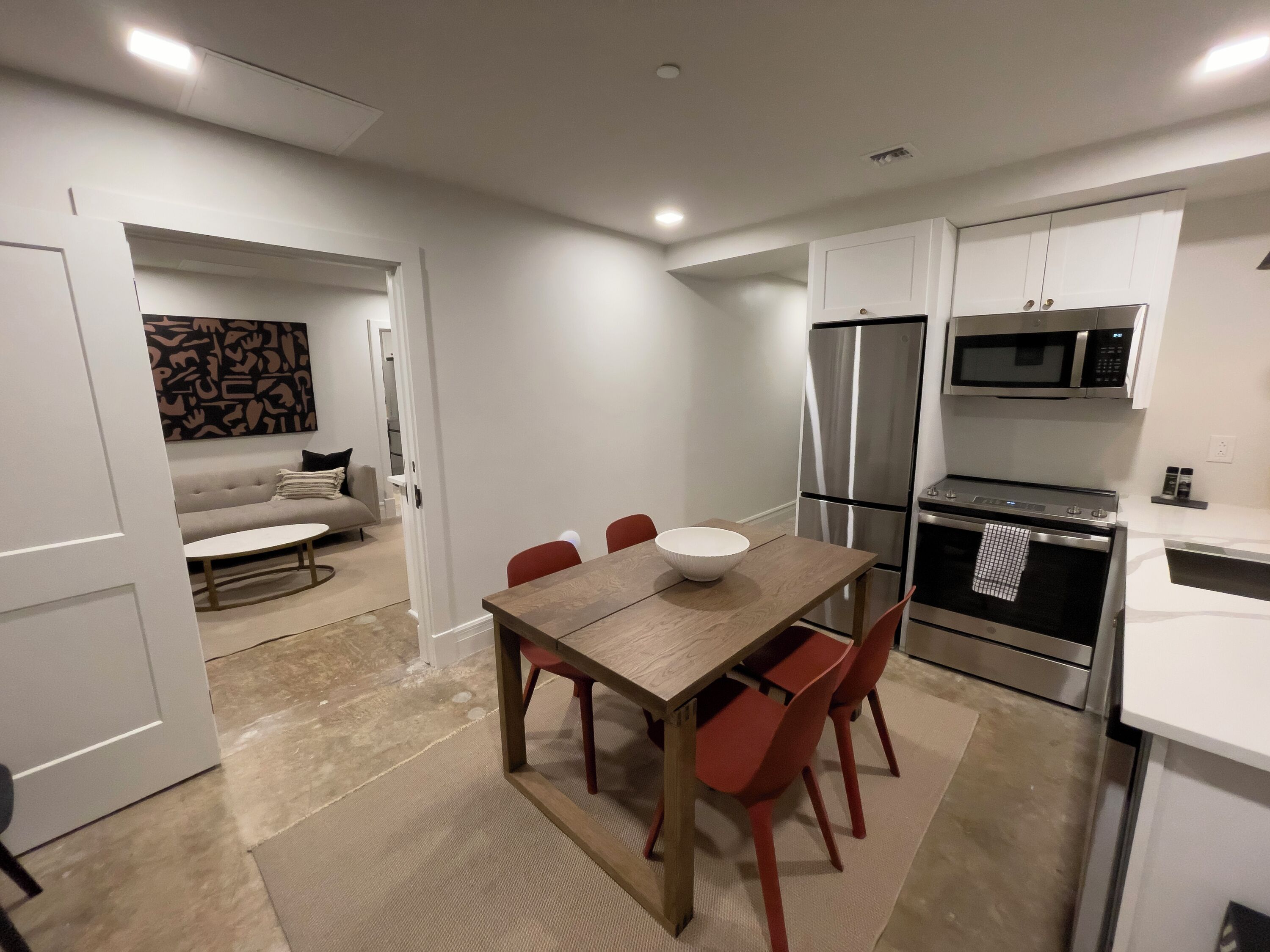 A compact kitchen with a dining table, chairs, a refrigerator, and a microwave.
