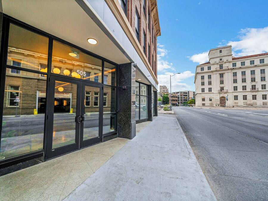 Un bâtiment moderne doté de grandes fenêtres en verre et d’un trottoir devant l’entrée.