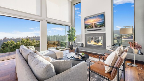 A modern living room with a large window, a fireplace, and a view of the city. - Summitridge - An Elegant Estate with Unobstructed City and Ocean Views (Beverly Hills)