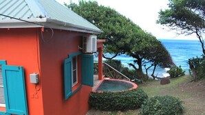 Un bâtiment rouge avec des volets bleus, un climatiseur et une petite piscine.
