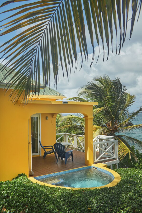 A yellow building with a pool, outdoor furniture, and palm trees.