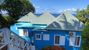 Une maison bleue avec un porche blanc et un petit escalier menant à l’entrée.